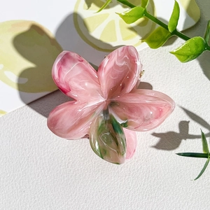 Vue détaillée d'une pince à cheveux en fleur de frangipanier avec texture marbrée rose