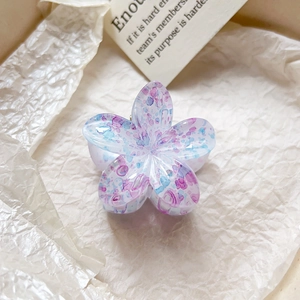Détail de taches d'encre violettes et bleues sur une pince à cheveux en forme de fleur
