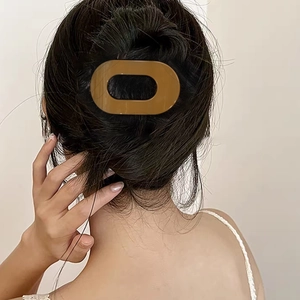 Minimalist brown oval cutout hair claw clip shown styling a high bun hairstyle