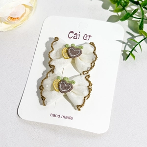 Vue détaillée des barrettes en dentelle fait main avec broderies de cœurs et de fruits
