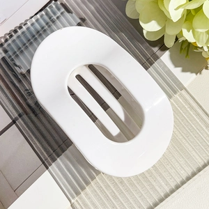 Detail view of large white glossy oval hair claw clip with minimalist hollow design