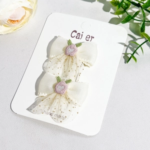 Détail de barrettes nœuds en tulle crème faites main avec paillettes et broderies