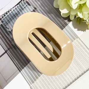 Macro detail of large cream beige oval hair claw clip with glossy resin finish