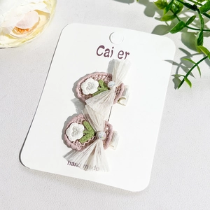 Détail de barrettes à fleurs crochetées à la main avec n&oelig;ud en résille rose sur carte