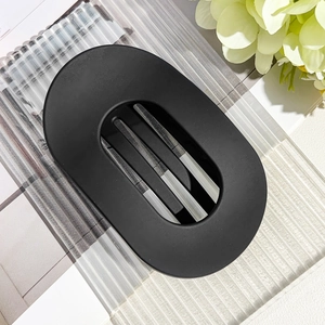 Macro detail of matte black oval hair claw with hollow design on textured acrylic