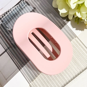 Detail of a large matte pink oval hair claw clip with a hollow striped design