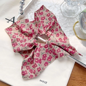 Chouchou à imprimé floral rose présenté sur un fond de toile de jute beige