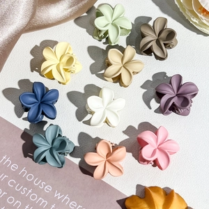 Flat lay of colorful 2.5cm matte plumeria flower hair claws in various pastel shades