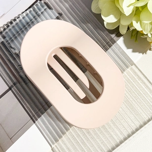 Detail view of pink matte oval hair claw clip on a decorative glass tray with soft lighting