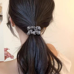 Elegant grey satin scrunchie for women holding a low ponytail on brown hair