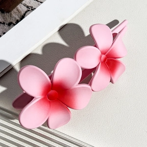 Detail of gradient pink plumeria hair clip with matte texture and sharp side lighting