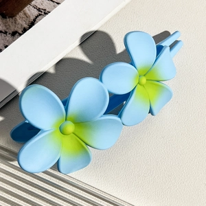 Detailed close-up of light blue matte frangipani hair clip with yellow gradient petals