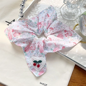 Vue détaillée du chouchou floral avec cœur en dentelle et motif cerise crochet