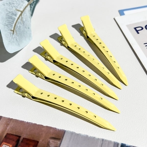 Dettaglio di 5 mollette professionali gialle per volume capelli su sfondo grigio chiaro