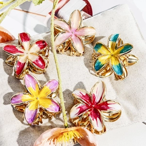 Macro view of five colorful enamel flower claw clips with golden metal finish