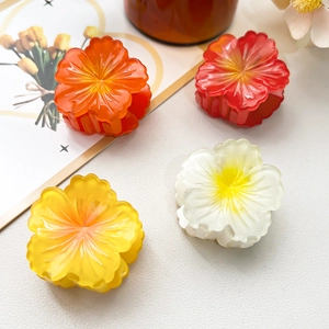 Close-up of four colorful frangipani flower hair claws in resin with a glossy finish