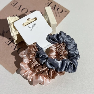 Detailed view of satin scrunchies set with pleated texture and soft champagne colors