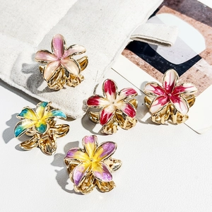 Macro detail of five mini gold-plated frangipani hair clips with colorful enamel finish
