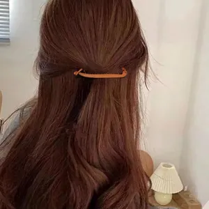 Minimalist amber banana hair clip on wavy brown hair in a casual half-up hairstyle