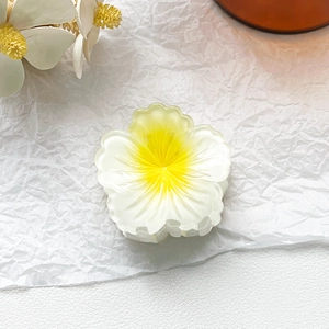 Detailed view of a realistic frangipani flower hair claw clip with yellow and white petals