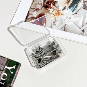 Detail of silver metal duckbill clips in a clear plastic storage box for hair styling