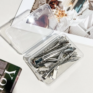 Silver metal hair clips with cooling holes in a transparent plastic storage box