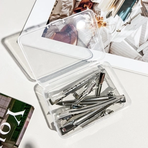 Detailed close-up of professional silver metal hair clips set in a clear storage box