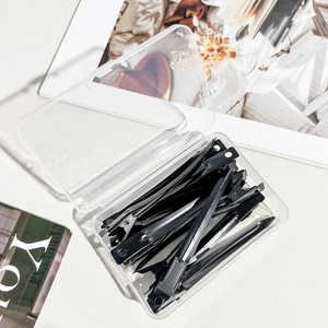 Set of black professional hair clips with a transparent storage box on a white surface