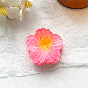 Detailed view of pink and yellow gradient frangipani flower hair claw clip hairpiece