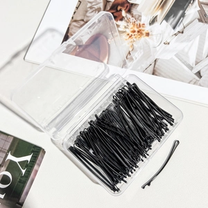 Set of black metal hair clips organized in a transparent storage box for hairstyling