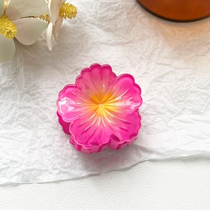 Close-up of tropical flower hair claw with vibrant pink and orange gradient petals