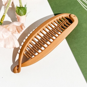 Detail view of matte brown banana hair clip with strong grip teeth on modern background