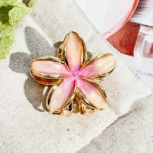 Detail of pink and orange gradient frangipani hair claw clip with golden alloy edges