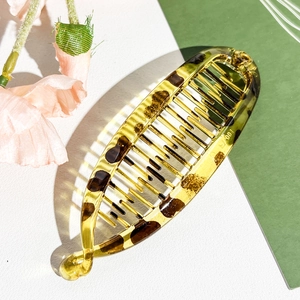 Macro detail of amber leopard print banana hair clip showing fine teeth and acrylic texture