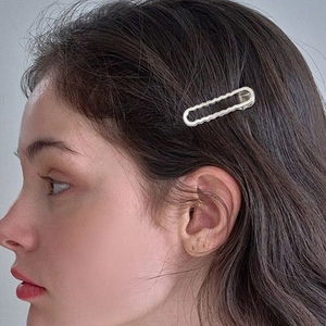 Barrette à cheveux ondulée en métal argenté avec design ovale évidé sur un modèle