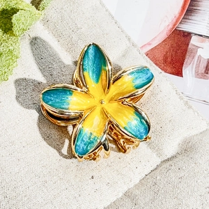 Detail of frangipani hair claw clip featuring yellow and blue gradient enamel finish