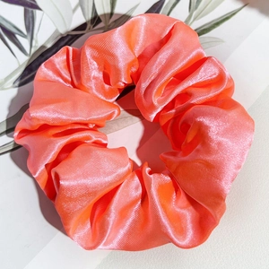 Détail du chouchou en satin orange corail vif avec une texture soyeuse et un éclat brillant