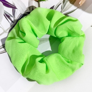 Vue détaillée du chouchou en satin vert néon avec texture plissée et couleur vibrante