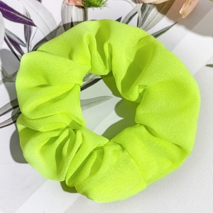 Détail du chouchou en satin jaune néon montrant la texture fine et les plis du tissu