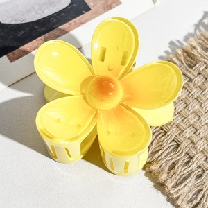 Vue détaillée d'une pince à cheveux fleur de frangipanier jaune sur cuir blanc