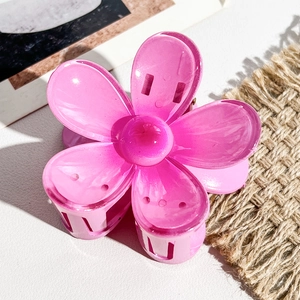 Détail macro d'une grande pince à cheveux fleur de frangipanier rose vif sur fond chic