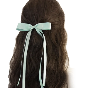 Barrette à nœud papillon en satin vert menthe avec longs rubans sur cheveux ondulés