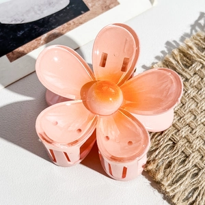 Détail d'une pince à cheveux fleur en résine pêche brillante avec une texture céramique