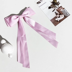 Gros plan d'une barrette à cheveux en ruban de satin rose pâle avec de longs pans soyeux