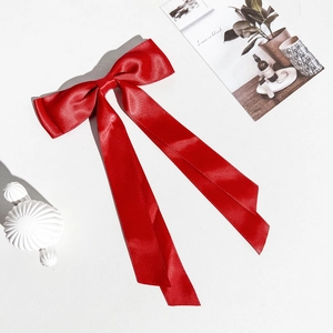 Détail d'un nœud papillon en satin rouge avec de longs rubans sur un fond minimaliste