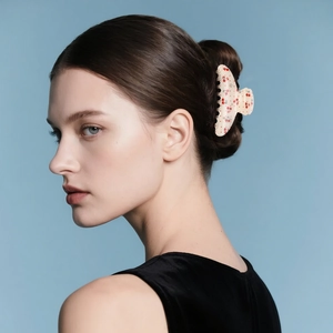 Floral cherry pattern hair claw clip with rhinestones worn on a model's dark hair