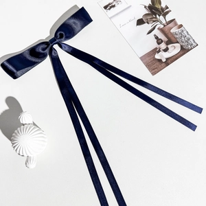 Détail d'un nɶud de cheveux en satin bleu marine élégant avec ruban sur une surface blanche
