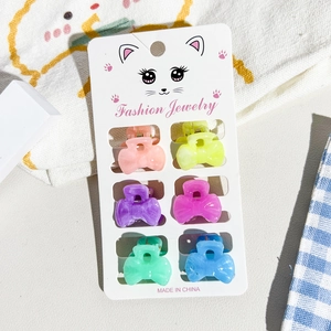 Close-up of six colorful mini bow hair claws on a decorative display card