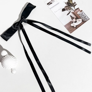 Détail du nœud papillon en satin noir avec de longs rubans sur un fond décoratif chic
