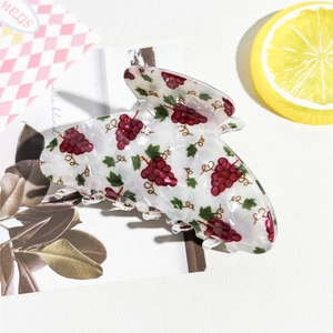 Vue détaillée de la pince à cheveux blanche avec motifs de raisins rouges et dents claires